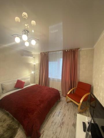 - une chambre avec un lit rouge et une chaise dans l'établissement Прекрасная квартира в новом доме возле метро, à Kiev
