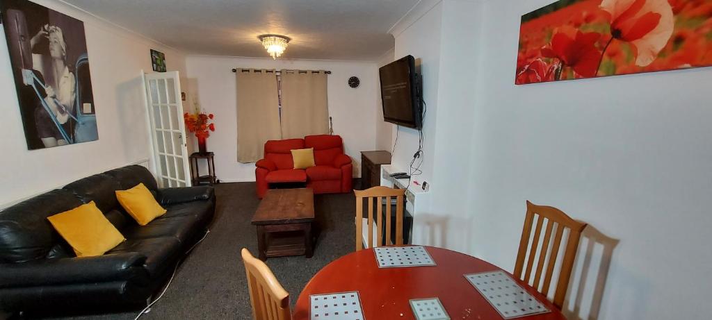 a living room with a black leather couch and a table at Comfortable 3 Bed House in Luton