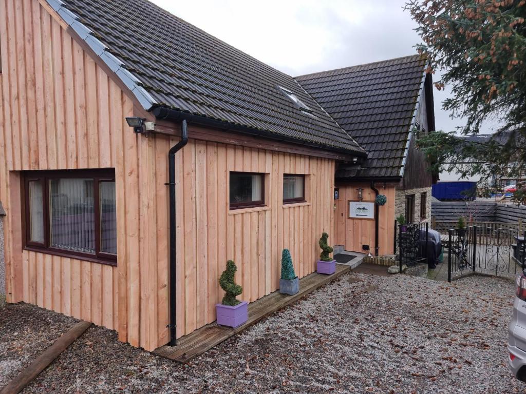 a wooden house with some plants in front of it at Carn Mhor Bed and Breakfast in Aviemore