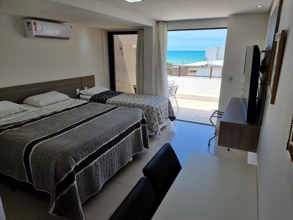 a bedroom with two beds and a balcony with the ocean at Gold Flat - Praia do Cabo Branco in João Pessoa