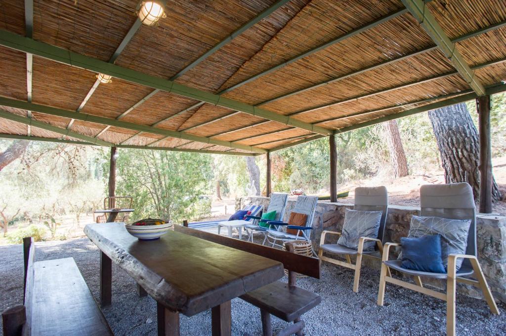 een houten tafel en stoelen onder een houten dak bij Casa Nocella a Bagnaia - Goelba in Portoferraio