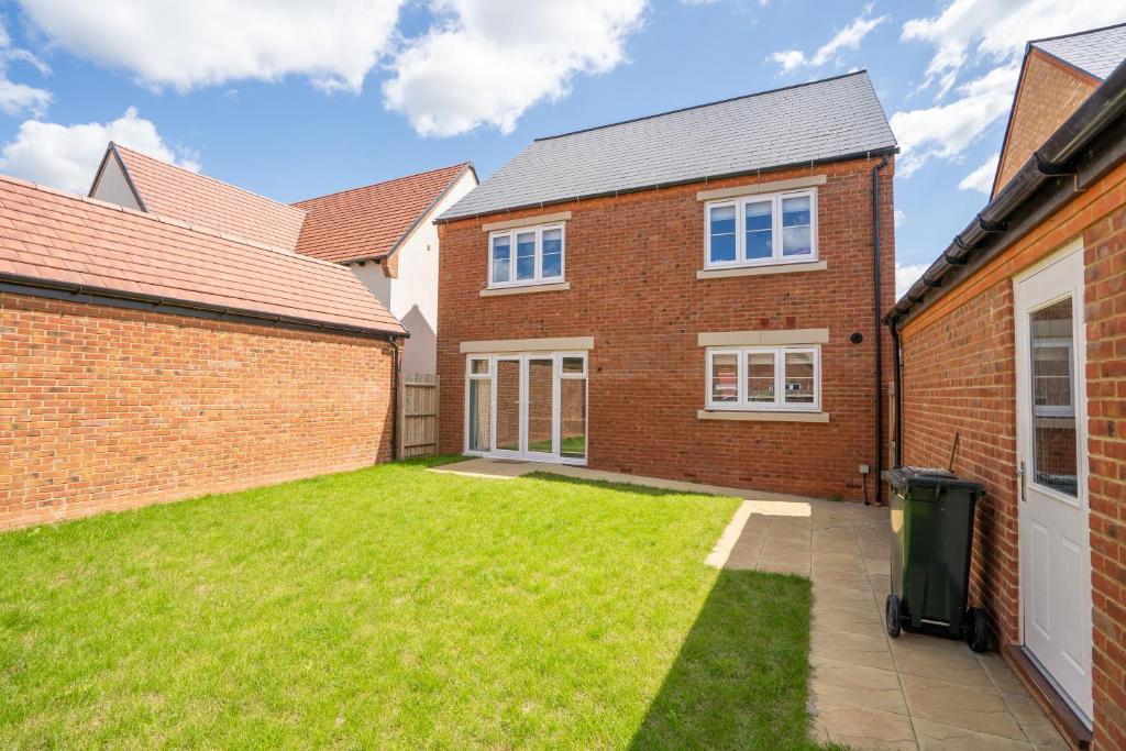 a brick house with a lawn in the yard at Immaculate 4-Bed House 5mins walk to Village shop in Bicester