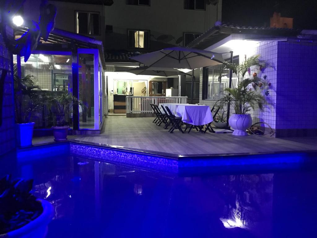 a table and chairs with an umbrella next to a pool at Hotel Pousada Irmaos Freyhardt in Rio de Janeiro