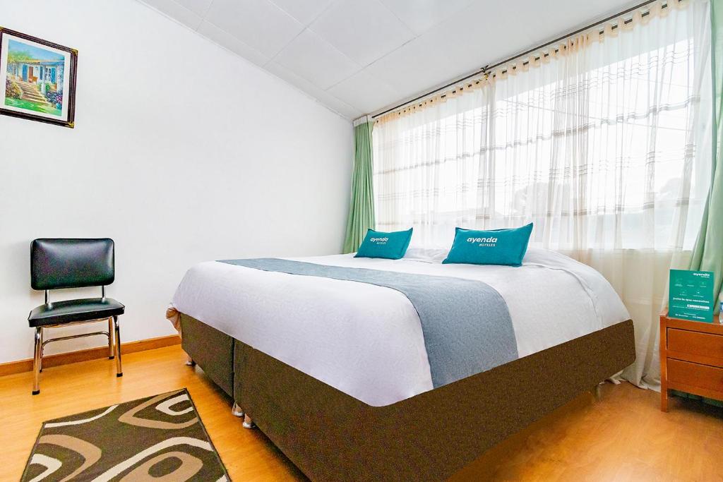 1 dormitorio con 1 cama y 1 silla frente a una ventana en Ayenda 1080 Bogotá Alpes Castellana, en Bogotá