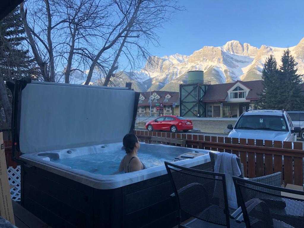 a woman in a hot tub with mountains in the background at Private Hot Tub / Yard /Patio - A/C- Mountain View Vacation Home in Canmore