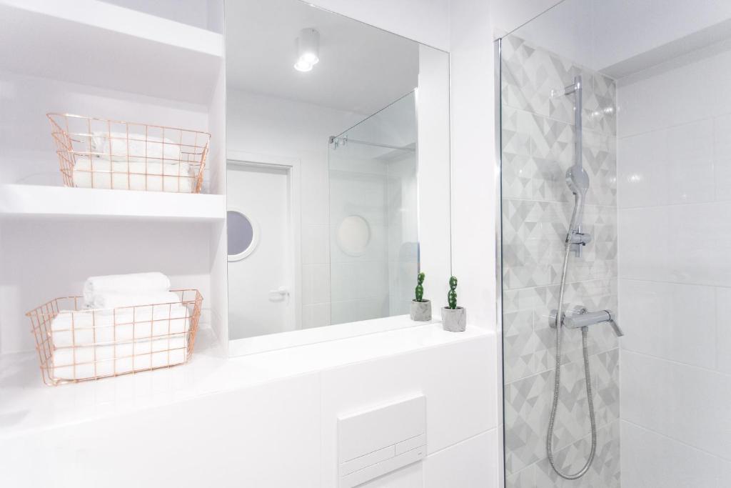 a white bathroom with a shower and a mirror at Check in Szczecin in Szczecin