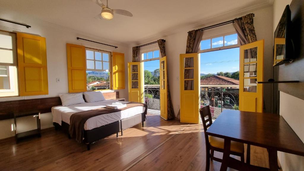 a bedroom with a bed and a table and a dining room at Pousada Imperial Cidade in Ouro Preto