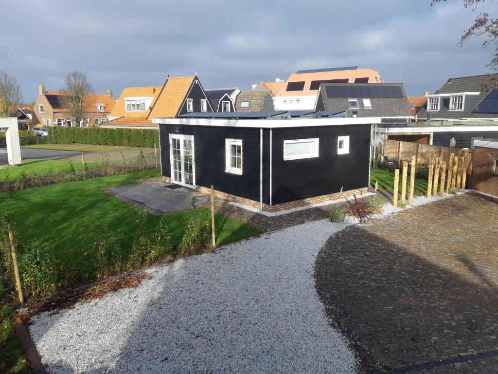 a black house with white windows in a yard at Recreatiewoning Den Hollander in Aagtekerke