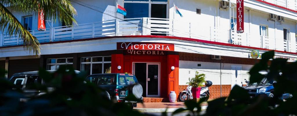 un cartello rosso sulla parte anteriore di un edificio di Hotel Victoria a Antsiranana