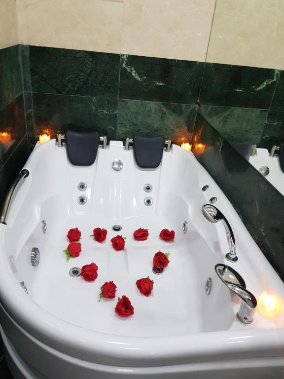 une baignoire blanche avec des roses rouges au milieu dans l'établissement Spa Mega Mall Monza National Arena, à Bucarest