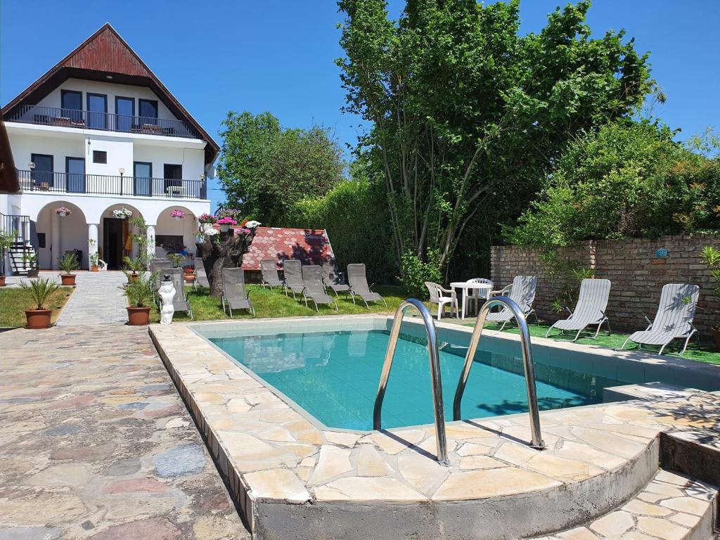 - une piscine avec une table et des chaises à côté d'une maison dans l'établissement Sipos Vendég és Apartmanház, à Balatongyörök