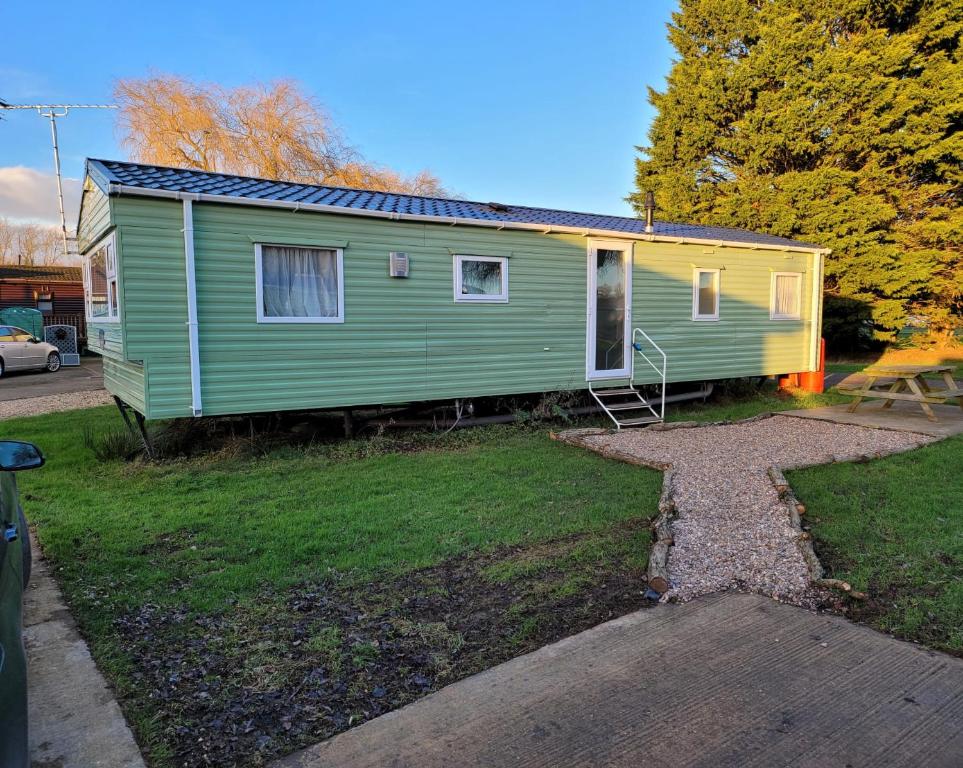 a green and yellow tiny house in a yard at Lovely Static 8 Bed Caravanat at Billing Aquadrome in Great Billing