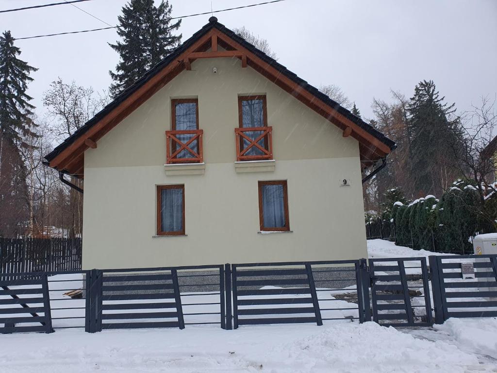 una pequeña casa blanca con techo de madera en la nieve en DOMEK BIAŁKA ZDRÓJ, en Szklarska Poręba