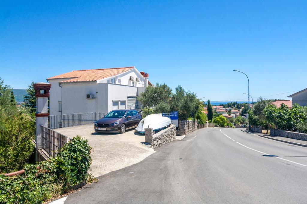 a house with a car parked on the side of a road at Apartments & Rooms Strčić Petra in Krk