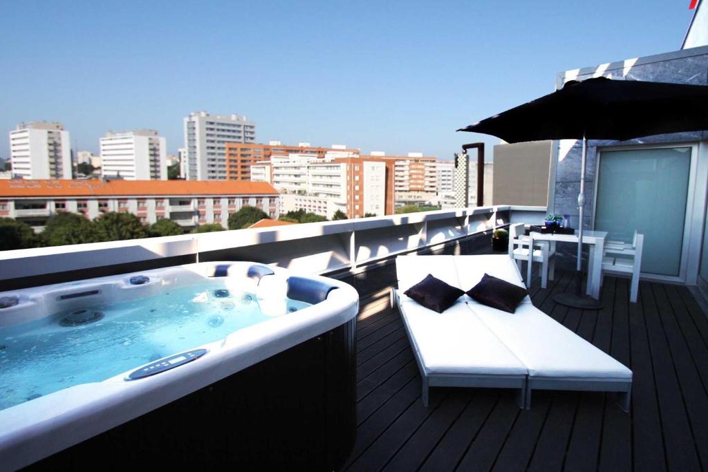 a hot tub on a balcony with an umbrella at BessaHotel Boavista in Porto