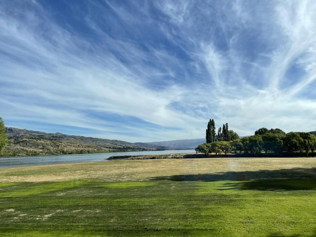 a grass field with a river and a blue sky at Pisa House Lakefront Boutique B&B in Cromwell