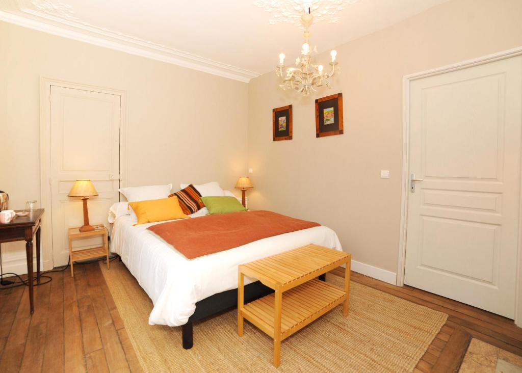 a bedroom with a bed and a table and a chandelier at Le Jardin Cathedrale in Chartres