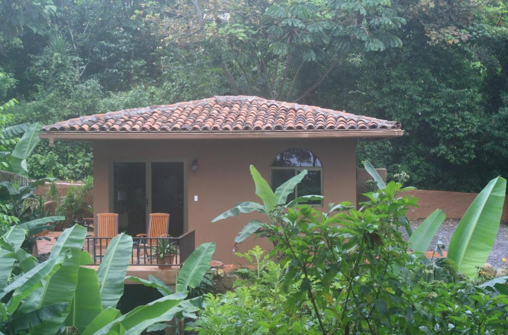 une petite maison avec un toit carrelé dans un jardin dans l'établissement The Casita at The Boquete Hacienda, à Boquete