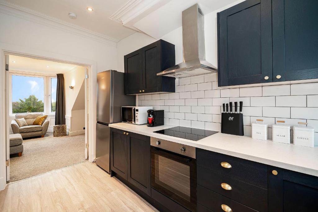 a kitchen with black cabinets and a living room at The Crossroads in Elderslie