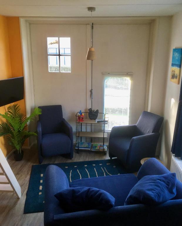 a living room with a blue couch and two chairs at Klinket Zoutelande in Zoutelande