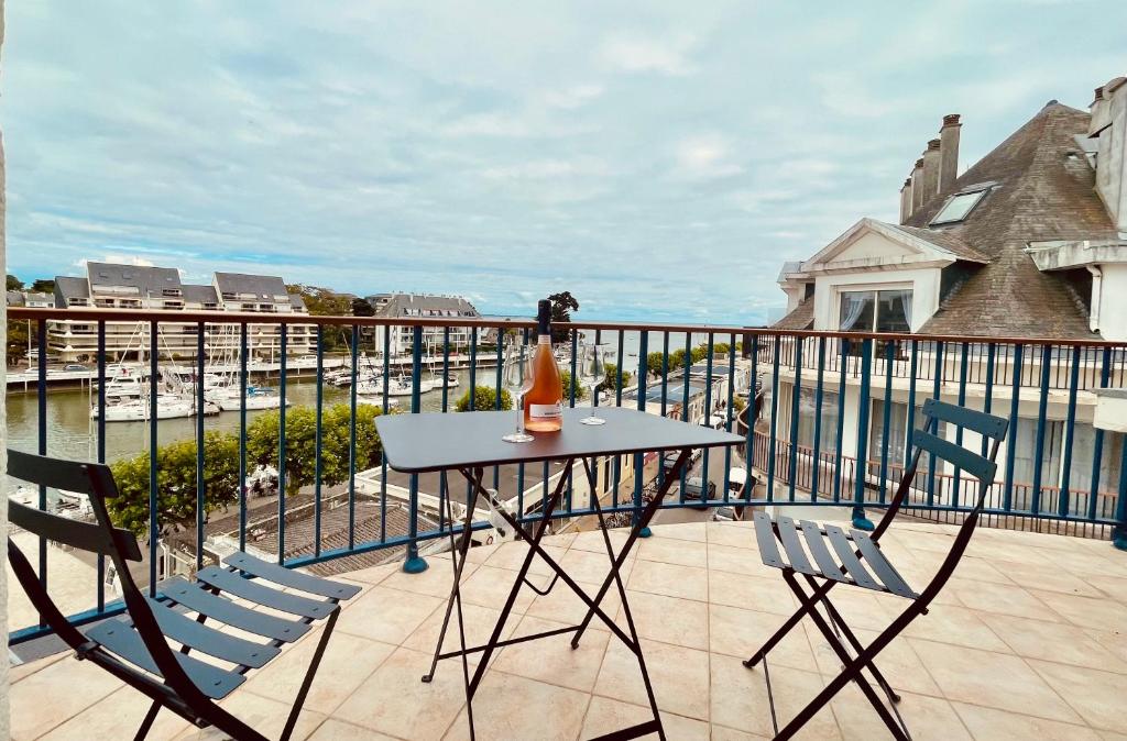 a table and two chairs on a balcony with a view at Superbe appartement 4 personnes Le Pouliguen avec vue magnifique sur le port et la mer in Le Pouliguen