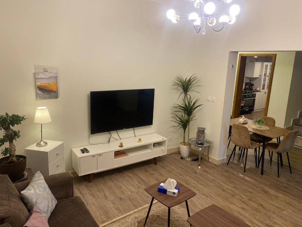 sala de estar con TV de pantalla plana en la pared en Sunset Alula Villa- العلا en Ar Riḩāb