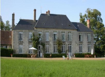 une grande maison avec un champ vert en face de celle-ci dans l'établissement Château de Sarceaux, à Aleçon