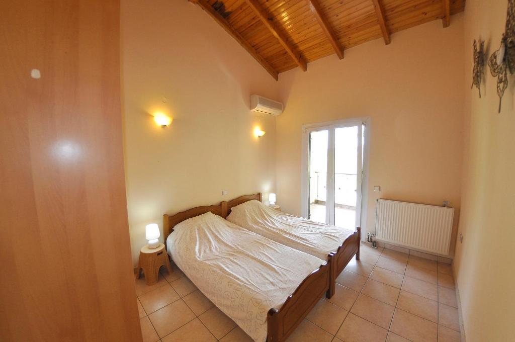 a bedroom with a bed in a room with a window at Corfu Villa Ermioli with Pool in Giannádes