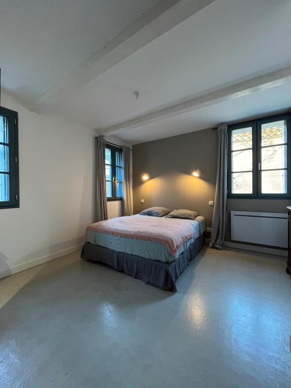 ein Schlafzimmer mit einem Bett in einem Zimmer mit Fenstern in der Unterkunft La maison Barberousse in Gruissan