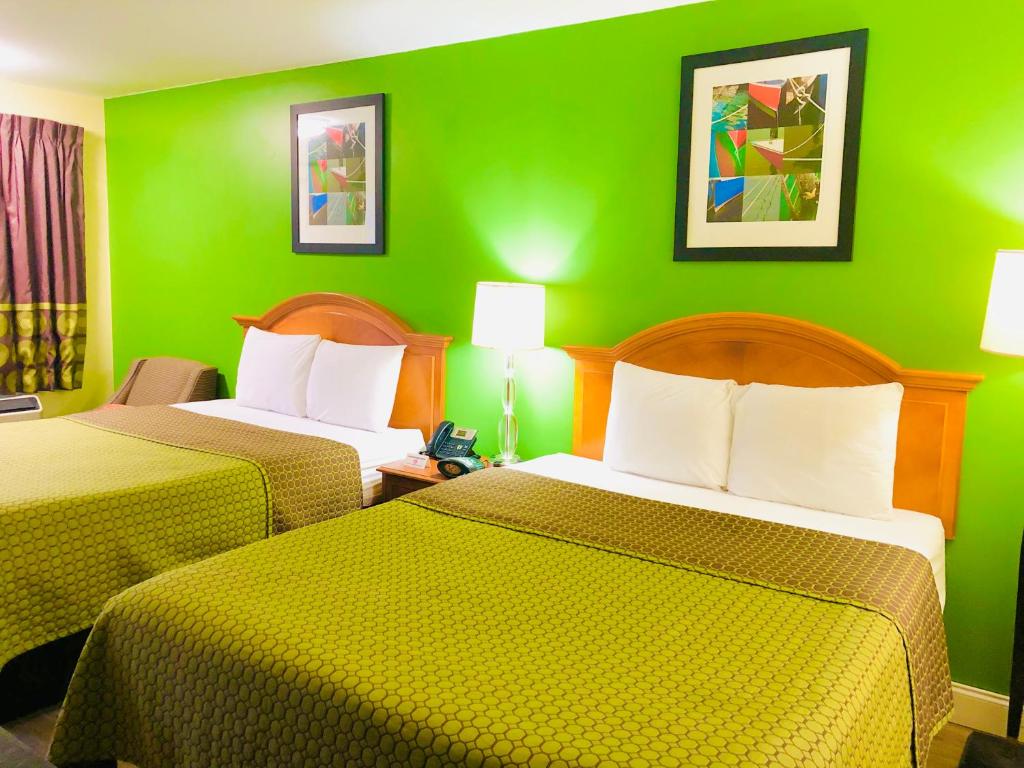 a hotel room with two beds with green walls at Classic Suites - Cleveland in Cleveland