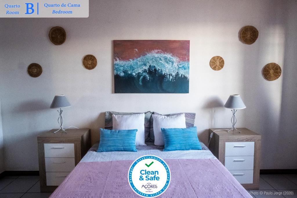 ein Schlafzimmer mit einem Bett mit blauen Kissen und einem Gemälde in der Unterkunft Casa dos Guerra in Ponta Delgada