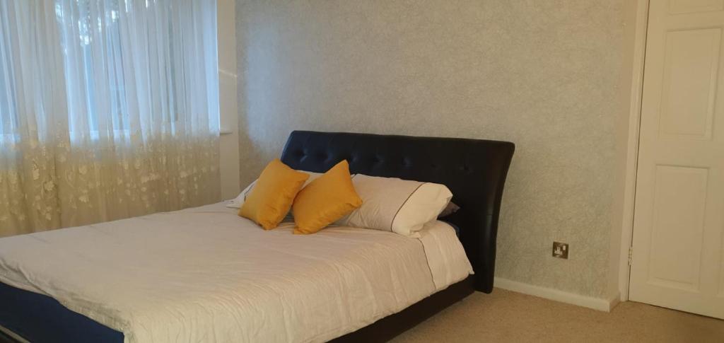 uma cama com duas almofadas amarelas em cima em 2 Bed semi-detached house em Poole