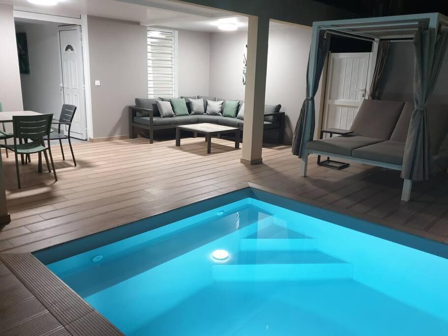 uma sala de estar com uma piscina azul num quarto em MARS ET VENUS LOCATION - piscine privée et chauffée em Sainte-Marie