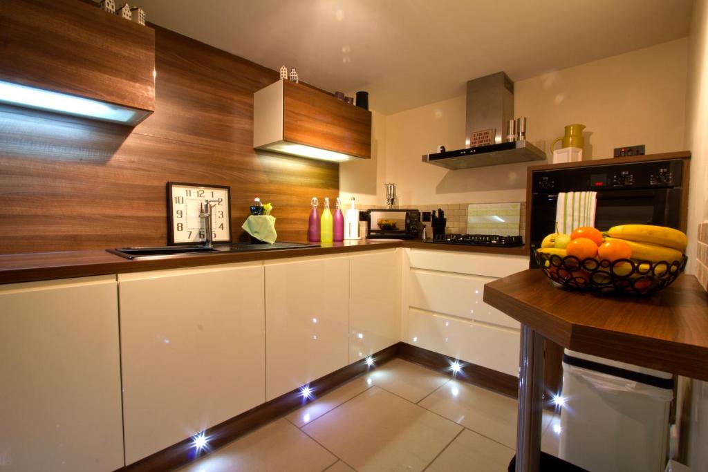 una cocina con armarios blancos y un bol de fruta en una barra en Heritage City - Central New Town Apartment, en Edimburgo