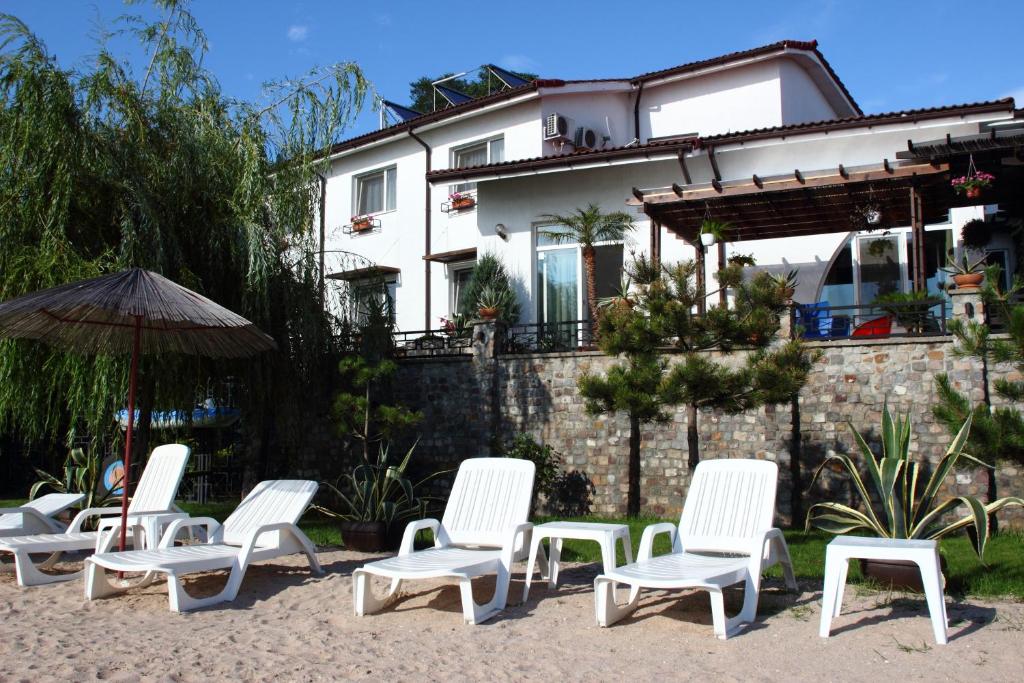 a group of chairs and an umbrella in front of a house at Vila Raluca in Eforie Nord