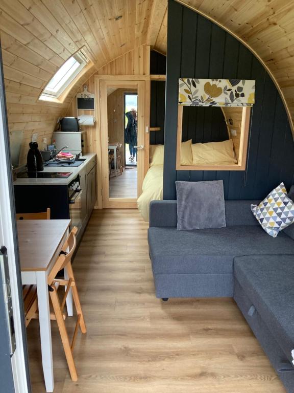 ein Wohnzimmer mit blauer Couch in einem winzigen Haus in der Unterkunft Owls Retreat Glamping Pod with Hot tub in Keith