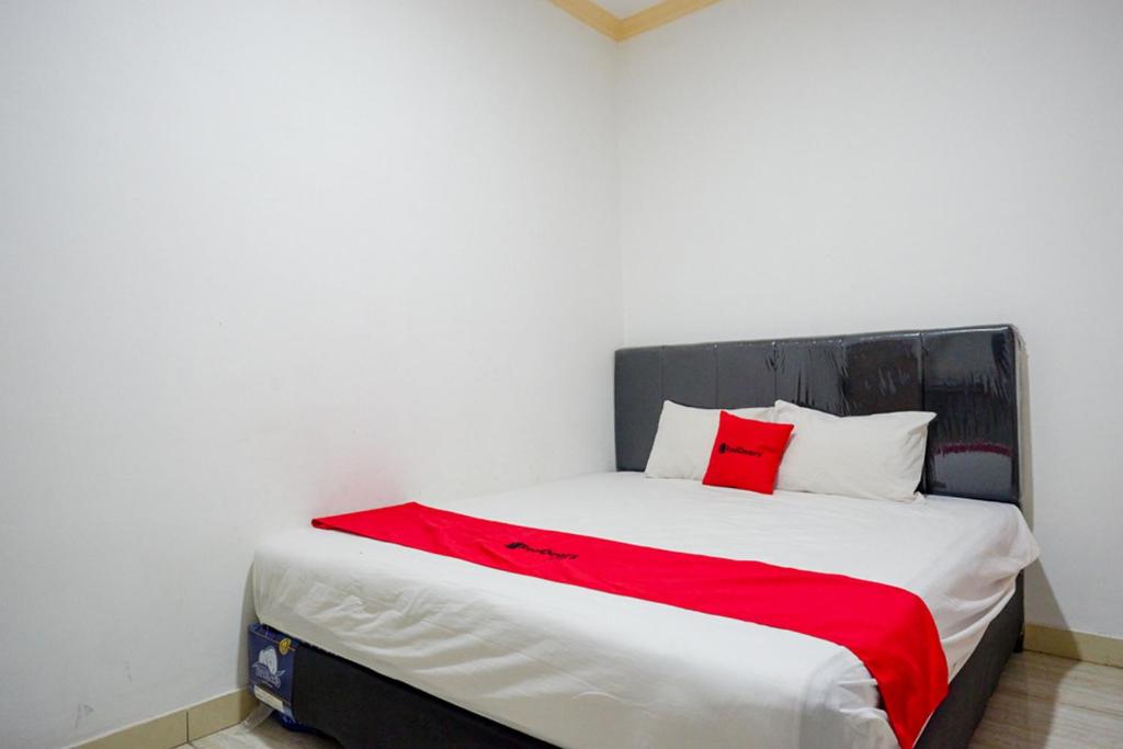 a bedroom with a bed with a red blanket on it at RedDoorz near RS Islam Faisal Makassar in Makassar