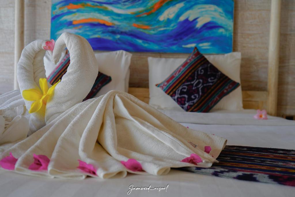 two swans wrapped in towels sitting on a bed at Java Wood in Gili Trawangan
