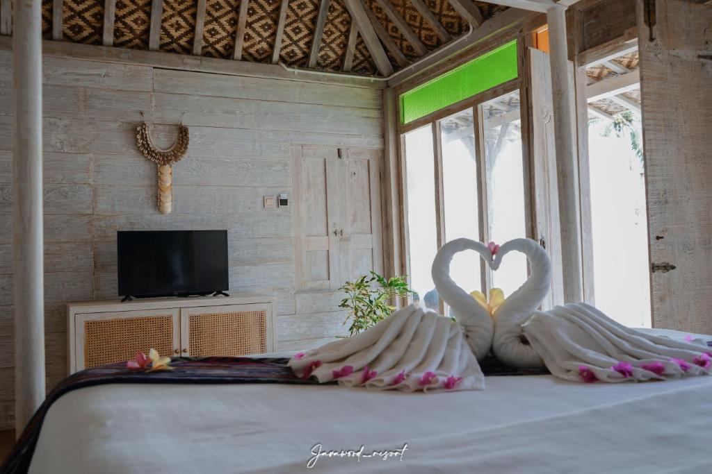 two swans sitting on a bed in a room at Java Wood in Gili Trawangan