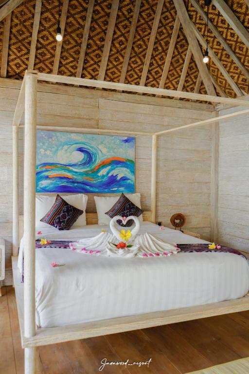 a bedroom with a white bed with a painting at Java Wood in Gili Trawangan