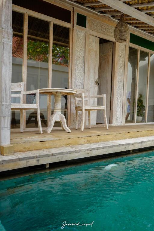 a table and chairs on a porch next to a pool at Java Wood in Gili Trawangan