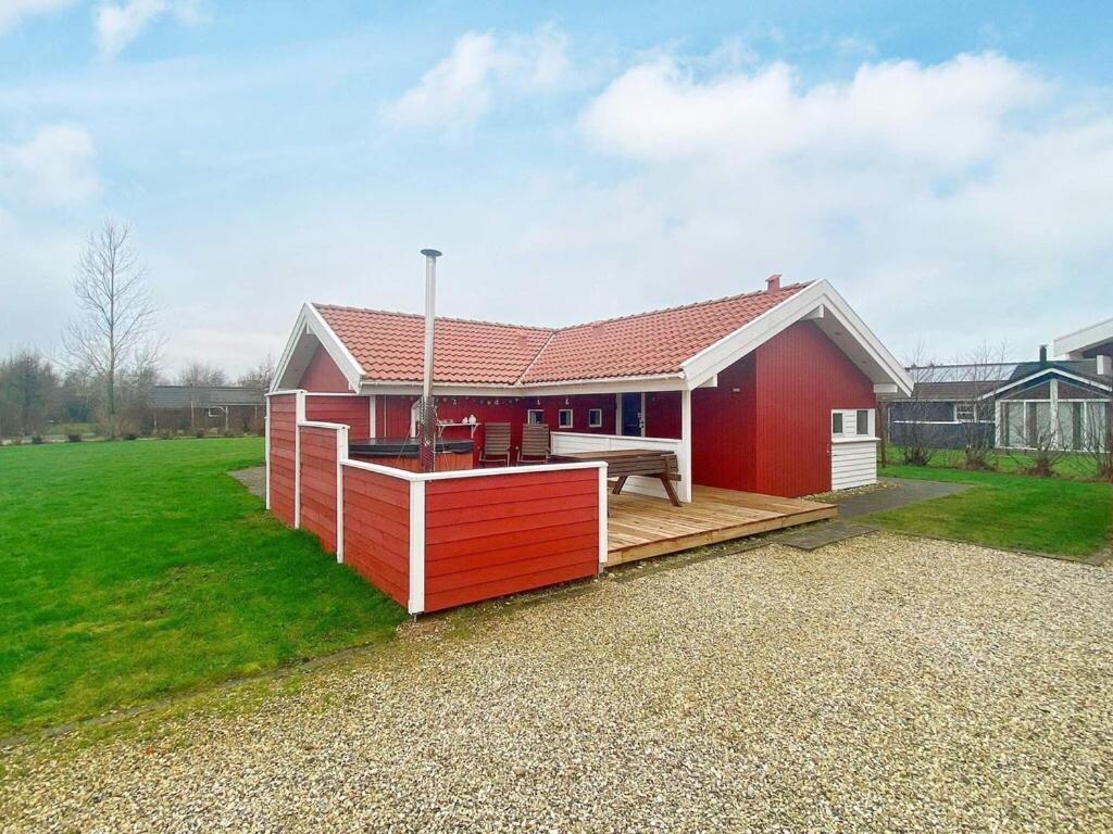 a red and white house with a bench on a deck at 6 person holiday home in Hemmet in Hemmet