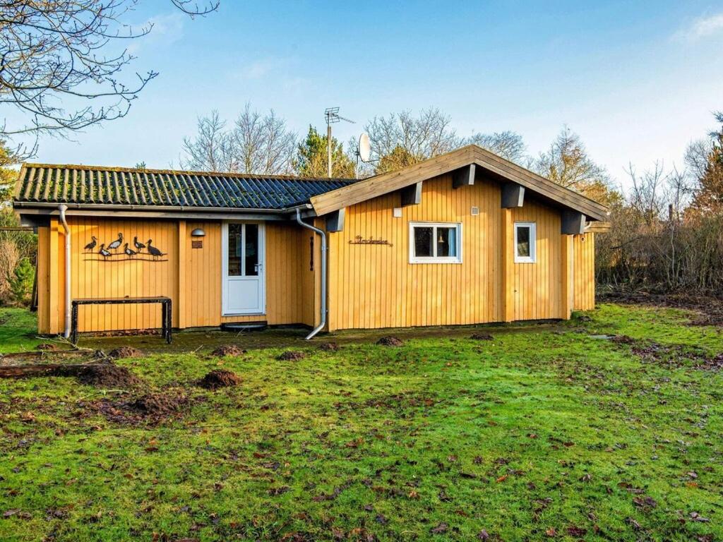 a small wooden house on a grass field at 4 person holiday home in Skjern in Lem