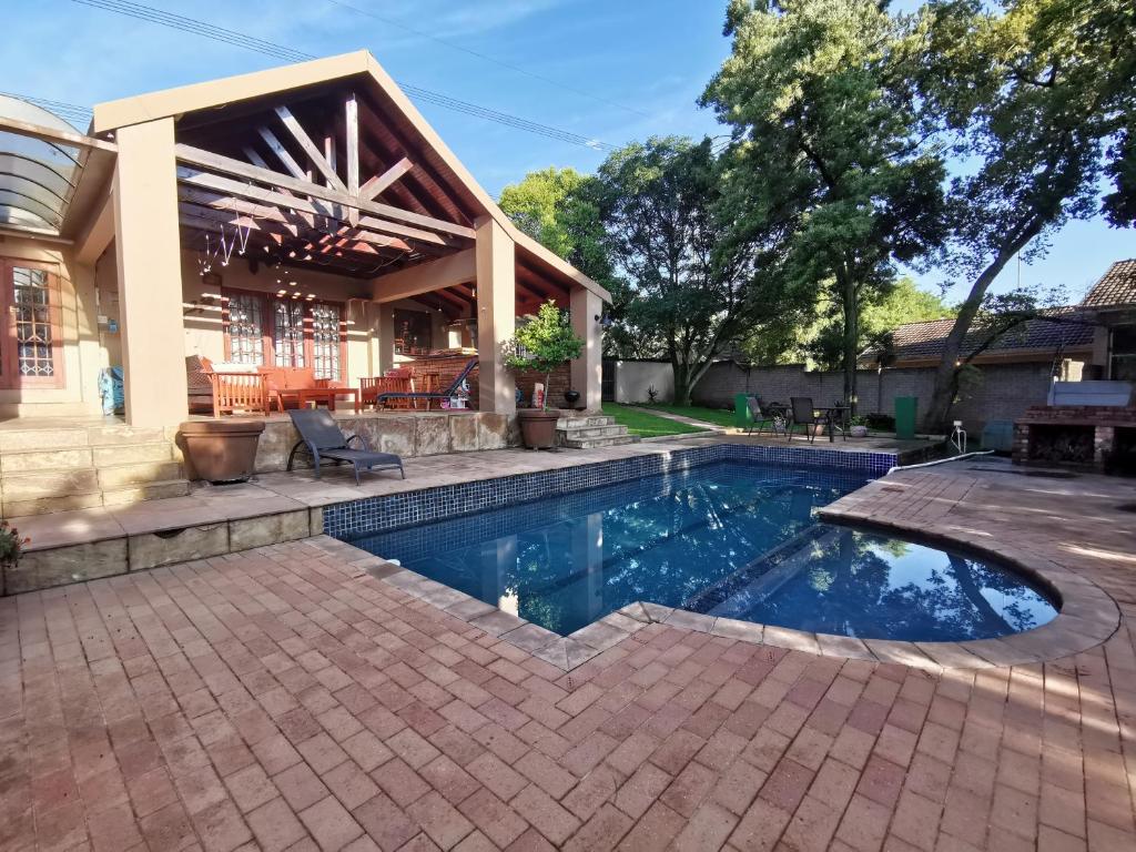 a swimming pool in front of a house at Paulshof Sandton Apartments - Hluhluwe Road Complex in Johannesburg