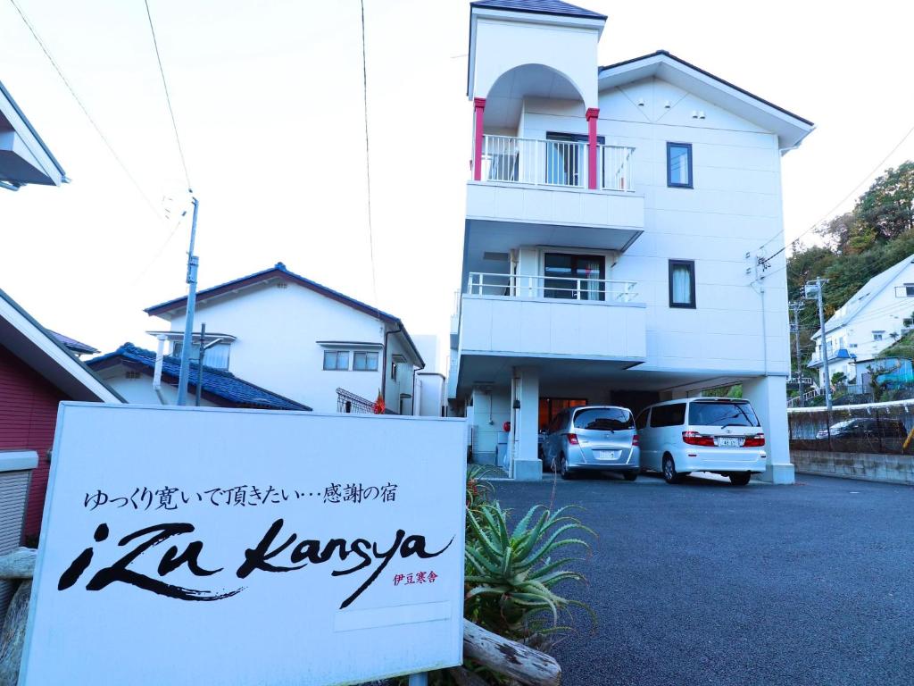 un edificio blanco con un cartel delante en Izu Kansya en Atami