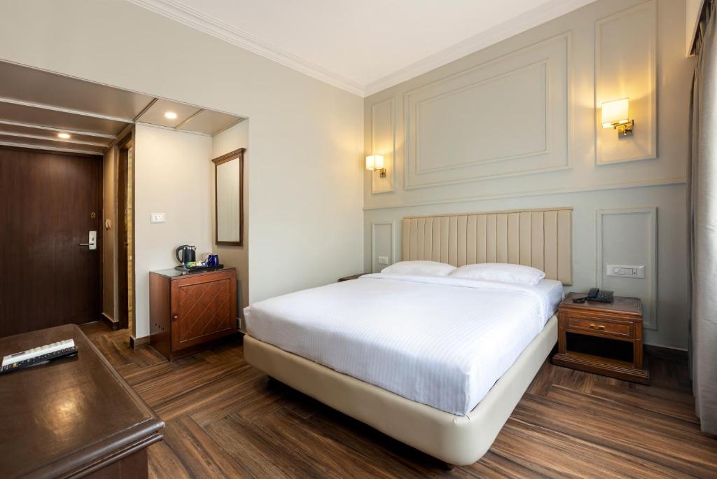 a bedroom with a large white bed and wooden floors at GRAND KALINGA HOTEL in Bangalore