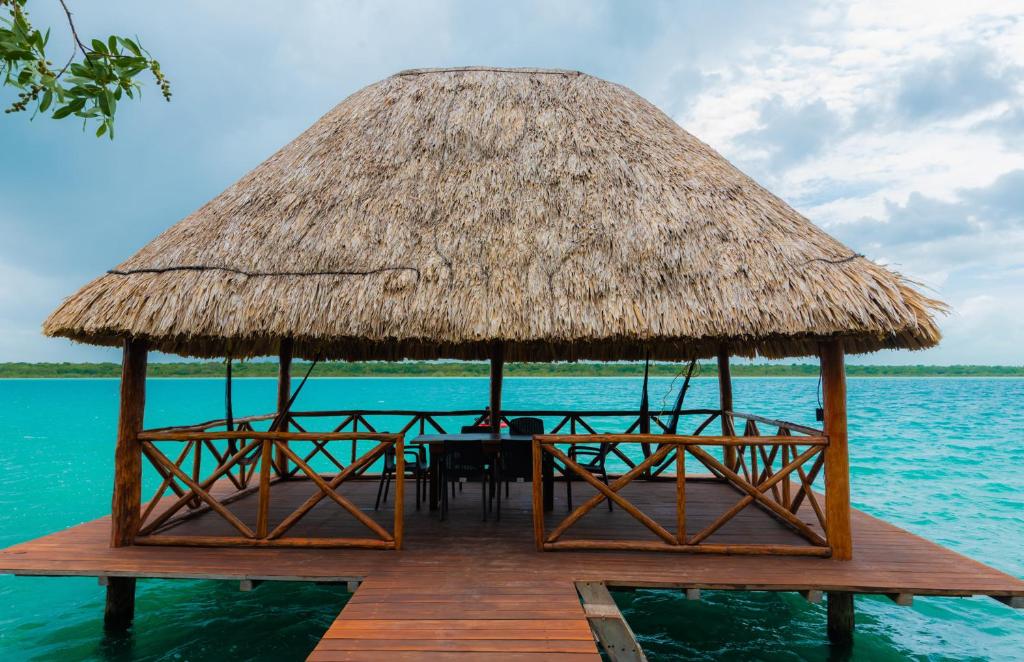 un restaurante en el agua con techo de paja en Laguna Bacalar Ichkiichpan, en Santa Cruz Chico