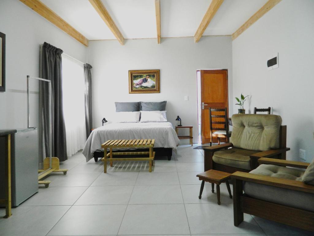 a bedroom with a bed and a couch and a chair at Kunsvilla in Durbanville