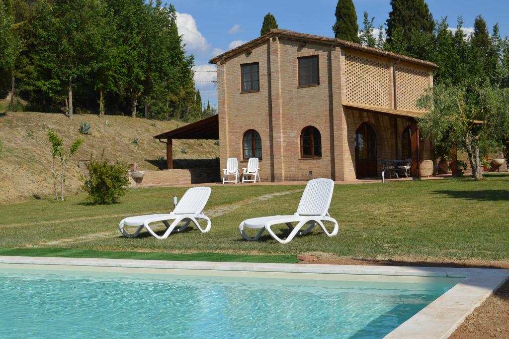 two white chairs and a house with a pool at Cottage with private swimming pool in Casetta