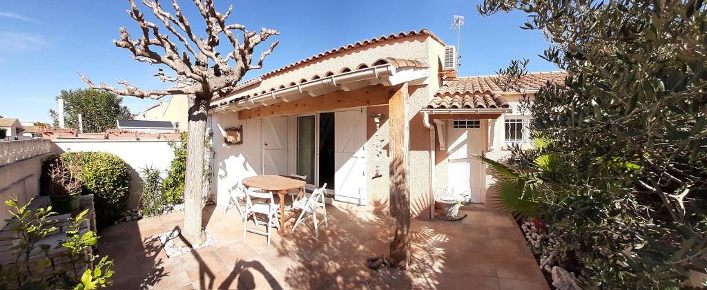 Cette petite maison blanche dispose d'une terrasse avec une table. dans l'établissement Location maison 4 pers Le Grau d'Agde 34, au Grau-dʼAgde